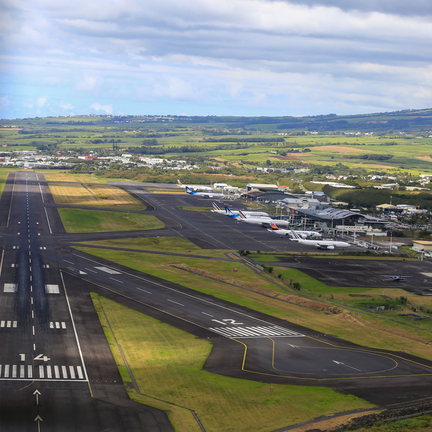 Vue aérienne de l'aéroport de La Réunion Roland-Garros (RUN) avec terminaux et piste en bord de mer