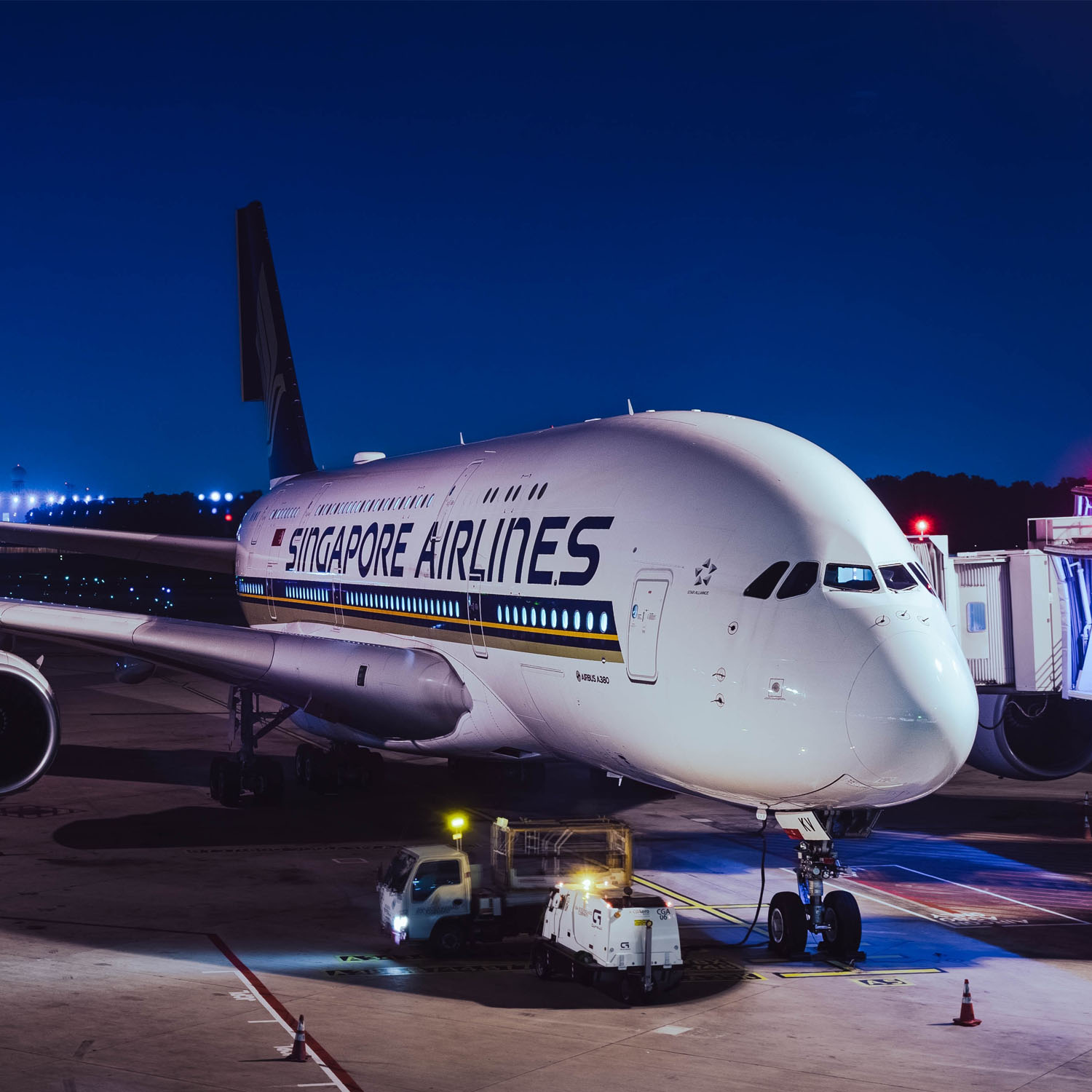 Avion de la compagnie Singapore Airlines devant un terminal d’aéroport durant la nuit